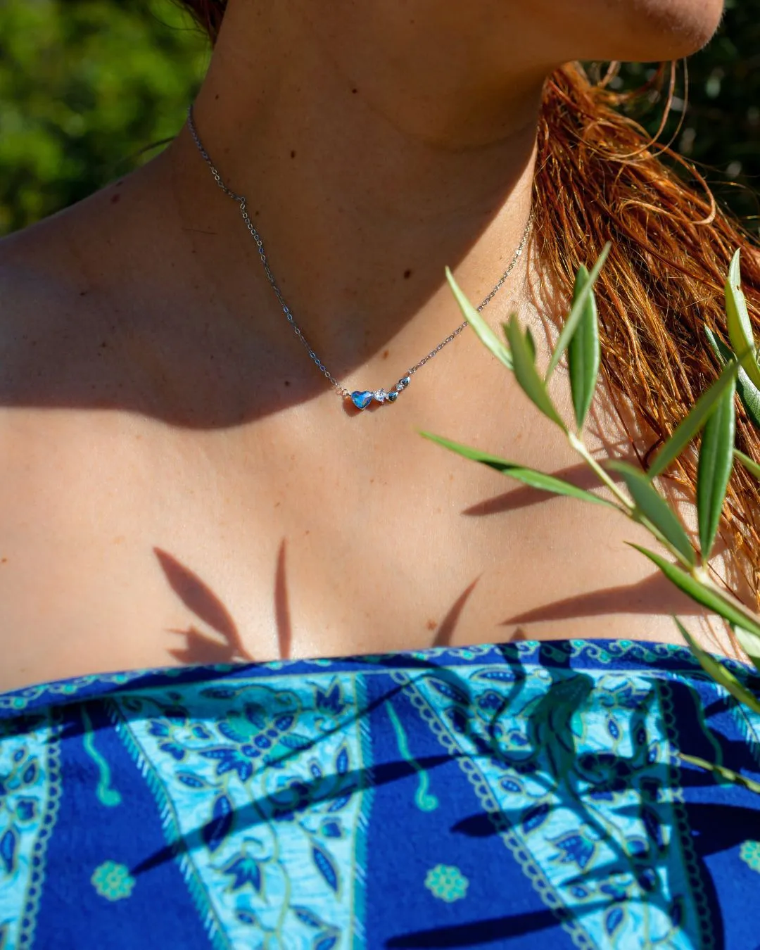 Srebrna ogrlica Diamond Glow Blue Heart sa plavim kristalnim srcem na modelu, letnji kadar u prirodi