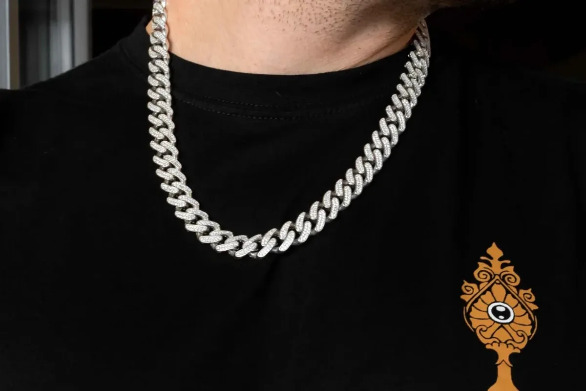 Masivna srebrna Cuban Link Iced Out ogrlica sa cirkonima na vratu, uz crnu majicu.