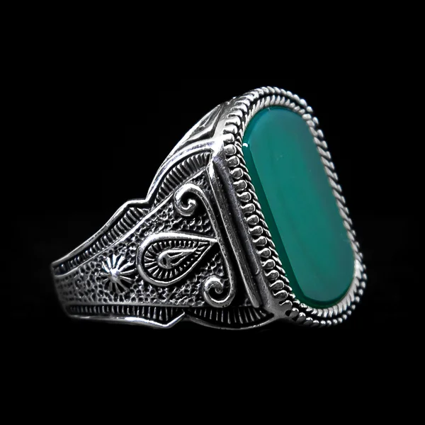 Srebrni prsten "Ahat Suza" pruža harmoničan sklad prirode i emocija. Sa prekrasnim zelenim ahatom u središtu, simboličkim dizajnom u obliku suze i sunca duž bočnih strana te izuzetno detaljnim gravurama, ovaj prsten je istinsko remek-delo nakita koje slavi prirodnu lepotu i emotivnu dubinu.